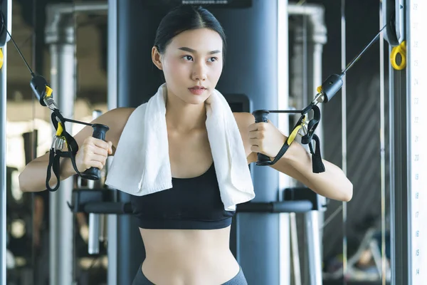 beautiful asian sport woman workout with weight machine to exercise in fitness beautiful woman lifts heavy dumbbell while training in the fitness Sports concept bodu builder  healthy lifestyle