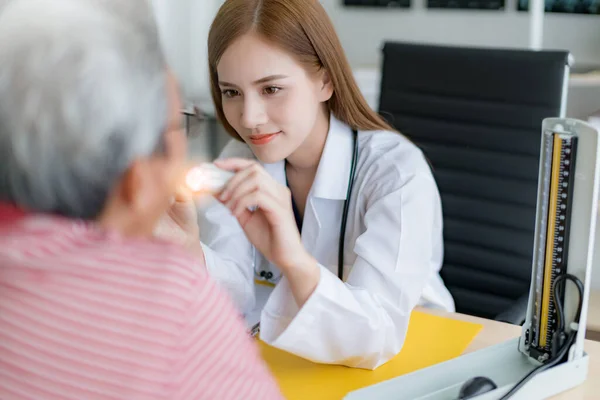 魅力的なアジア人医師女性が病院で高齢アジア人患者の舌喉体系を調べる — ストック写真