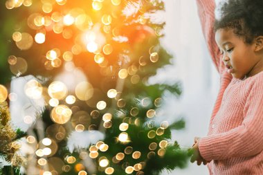 Afrikalı kadın çocuk Noel ağacını eğlenceli ve neşeli Noel şenlik fikirleriyle süsledi.