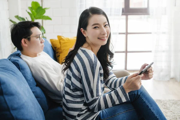 快乐的亚洲人甜蜜的夫妻一起享受智能手机游戏客厅的背景 — 图库照片