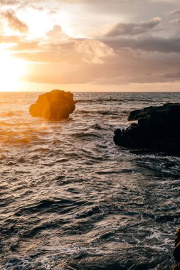 Gün batımında kayalık oluşum uçurumlarına düşen dalgalar güzel bir ışıkla