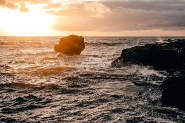 Gün batımında kayalık oluşum uçurumlarına düşen dalgalar güzel bir ışıkla