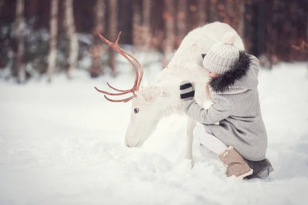 Küçük Kız Kış Ormanında Beyaz Bir Ren Geyiğiyle Oturuyor — Stok fotoğraf