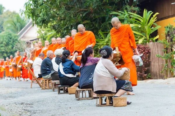 Luang Prabang, Laos - Mar 06 2015: Buddhistiska munkar samla allmosor på morgonen. Traditionen av allmosan till munkar i Luang Prabang har förlängts till turister. — Stockfoto