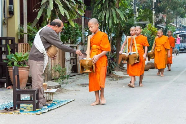 Luang Prabang, Laos - Mar 06 2015: Buddhistiska munkar samla allmosor på morgonen. Traditionen av allmosan till munkar i Luang Prabang har förlängts till turister. — Stockfoto