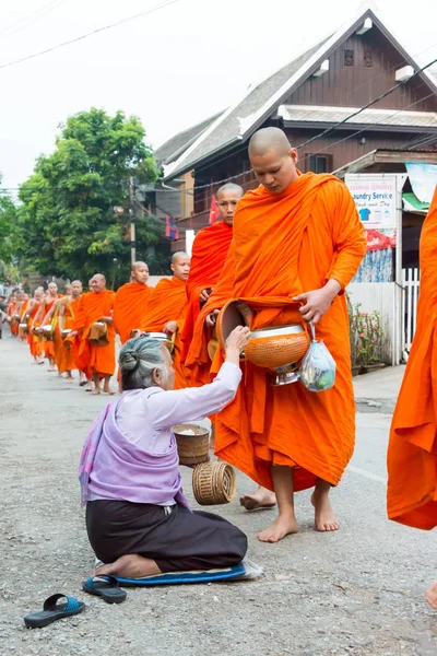 Luang Prabang, Laos - Mar 06 2015: Buddhistiska munkar samla allmosor på morgonen. Traditionen av allmosan till munkar i Luang Prabang har förlängts till turister. — Stockfoto