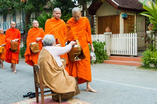 Luang Prabang, Laos - Mar 06 2015: Buddhist monks collecting alms in the morning. The tradition of giving alms to monks in Luang Prabang has been extended to tourists. — Stock Photo, Image