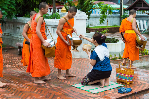 Luang Prabang, Laos - Jun 12 2015: Buddhist alms giving ceremony in the morning. The tradition of giving alms to monks in Luang Prabang has been extended to tourists.