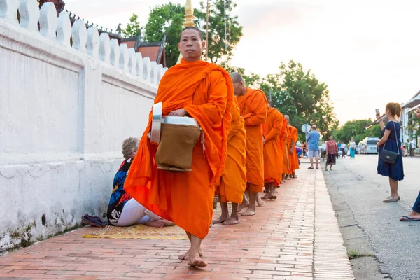 Luang Prabang, Laos - Jun 13 2015: Buddhist alms giving ceremony in the morning. The tradition of giving alms to monks in Luang Prabang has been extended to tourists. — Stock Photo, Image
