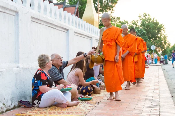 Luang Prabang, Laos - Jun 13 2015: Boeddhistische aalmoes geven ceremonie in de ochtend. De traditie van het geven van aalmoes aan monniken in Luang Prabang is uitgebreid tot toeristen. — Stockfoto