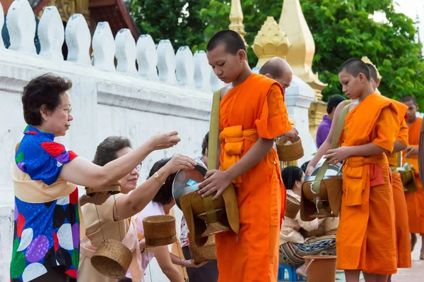 Luang Prabang, Laos - Jun 13 2015: Boeddhistische aalmoes geven ceremonie in de ochtend. De traditie van het geven van aalmoes aan monniken in Luang Prabang is uitgebreid tot toeristen. — Stockfoto