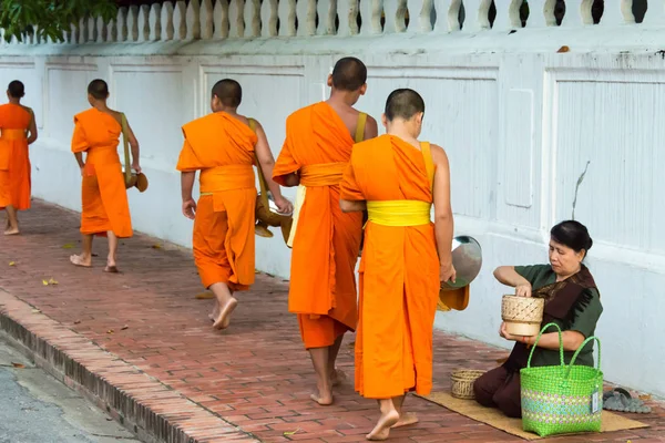 Luang Prabang, Laos - Jun 13 2015: Buddhist alms giving ceremony in the morning. The tradition of giving alms to monks in Luang Prabang has been extended to tourists. — Stock Photo, Image