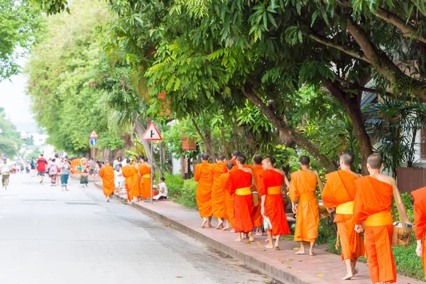 Luang Prabang, Laos - Jun 13 2015: Boeddhistische aalmoes geven ceremonie in de ochtend. De traditie van het geven van aalmoes aan monniken in Luang Prabang is uitgebreid tot toeristen. — Stockfoto