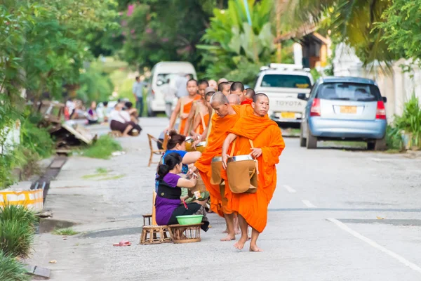 Luang Prabang, Laos - Jun 13 2015: Boeddhistische aalmoes geven ceremonie in de ochtend. De traditie van het geven van aalmoes aan monniken in Luang Prabang is uitgebreid tot toeristen. — Stockfoto