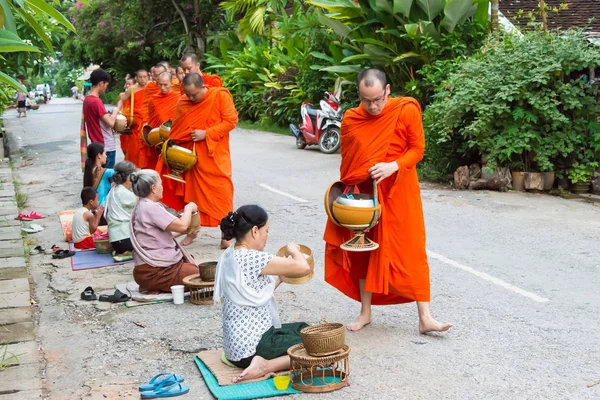 Luang Prabang, Laos - 14 jun 2015: Ceremonia de limosna budista por la mañana. La tradición de dar limosna a los monjes en Luang Prabang se ha extendido a los turistas . — Foto de Stock