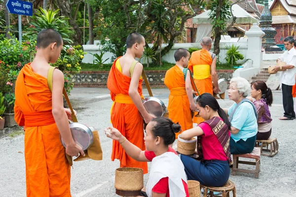 Luang Prabang, Laos - Jun 14 2015: Boeddhistische aalmoes geven ceremonie in de ochtend. De traditie van het geven van aalmoes aan monniken in Luang Prabang is uitgebreid tot toeristen. — Stockfoto