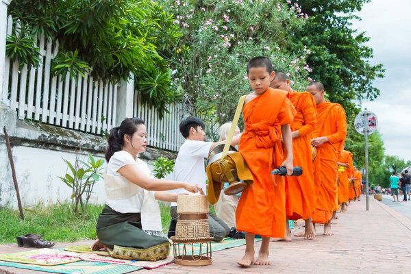 Luang Prabang, Laos - Jun 15 2015: Buddhist alms giving ceremony in the morning. The tradition of giving alms to monks in Luang Prabang has been extended to tourists.