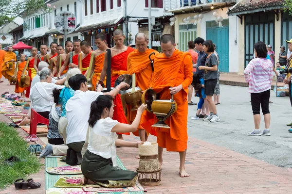 Luang Prabang, Laos - Jun 15 2015: Buddhist alms giving ceremony in the morning. The tradition of giving alms to monks in Luang Prabang has been extended to tourists. — Stock Photo, Image