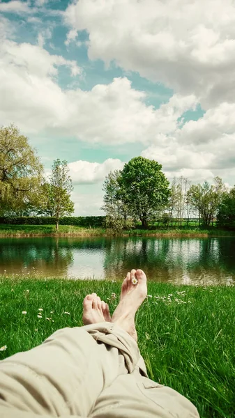 Legs and feet relaxing in front of serene fresh water pond