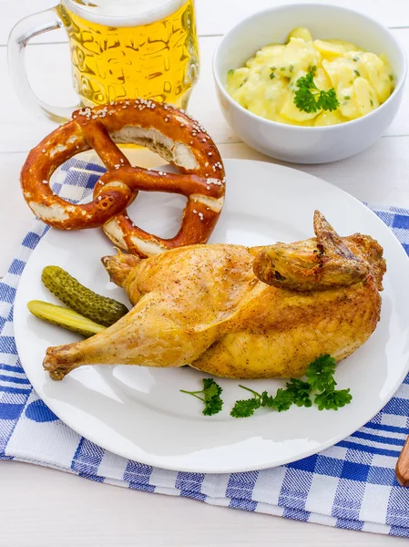 Half roast chicken, beer, pretzel and potato salad — Stock Photo, Image