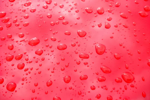 Dešťové kapky na červeném pozadí — Stock fotografie