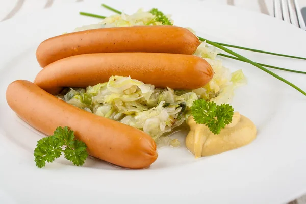 Three mini wieners on fried cabbage with mustard — Stock Photo, Image