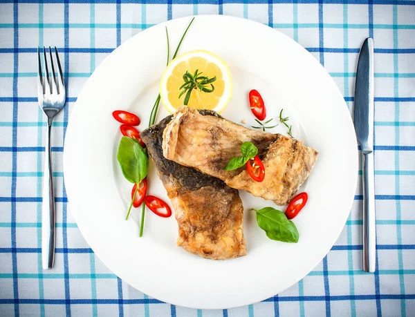 Pescado frito en plato blanco y tenedor, cuchillo — Foto de Stock