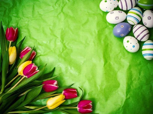 Wielkanocnego jajka, tulipany na zielony zmięty papier pakowy — Zdjęcie stockowe