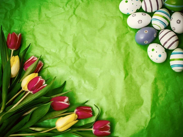 Východní vajíčka, tulipány na zelené zmačkané balicí papír — Stock fotografie