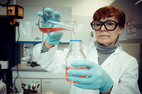 Araştırma görevlisi laboratuvar kırmızı sıvı ile çalışır. — Stok fotoğraf