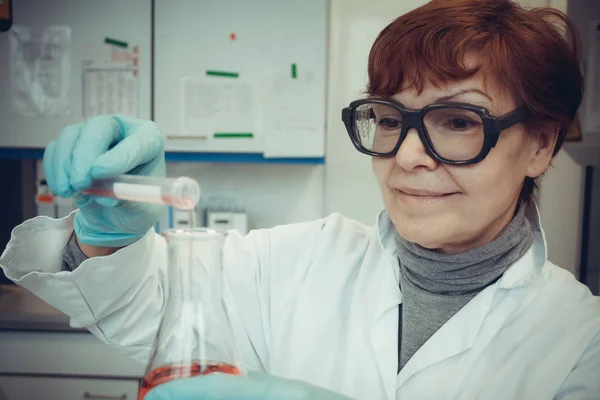 Assistente di ricerca lavora con liquido rosso in laboratorio — Foto Stock