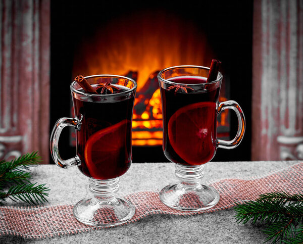Two mulled wine glasses by the fireplace