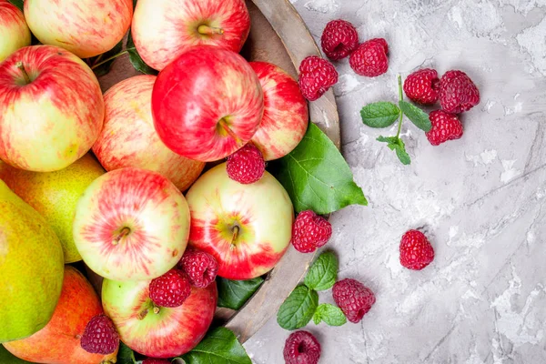 Fresh raspberries and apples on old wooden plate on a concrete background. Healthy concept. Natural healthy food. — Stock Photo, Image