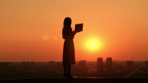 Woman with computer outdoors cityscape at sunrise — Stok video
