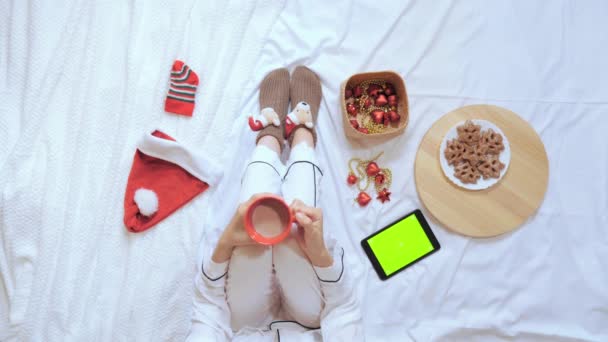 Vista dall'alto femminile beve un drink da una tazza rossa in camera da letto vigilia di Natale — Video Stock