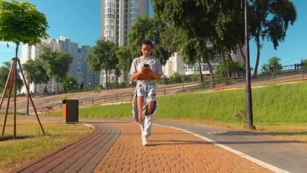 Leende blandras millennials promenad utomhus med hjälp av smartphone läsa goda nyheter — Stockvideo