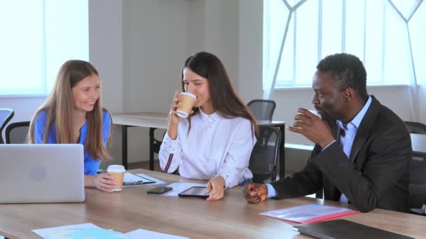 Mitarbeiter mit Tasse und Getränk sitzen am Schreibtisch und haben Spaß — Stockvideo