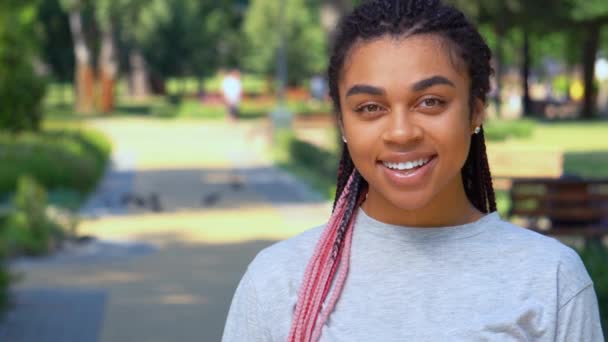 Vue de face jeune mixte femme rire regardant caméra dans le parc — Video