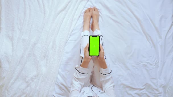 Выше вид женщины с помощью мобильного сидит в спальне — стоковое видео