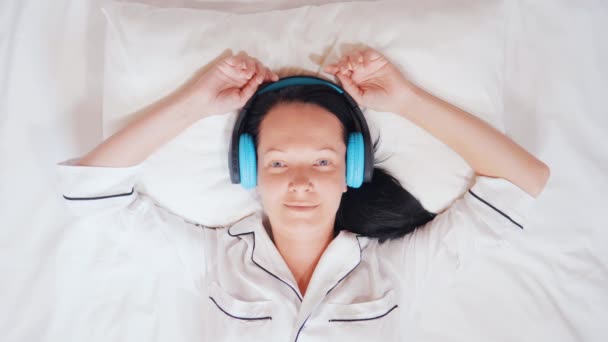 Feliz caucásico morena escuchar una canción en la cama — Vídeos de Stock