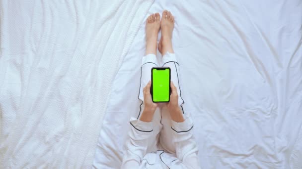 Выше зрения женщина с помощью смартфона сидит в спальне — стоковое видео