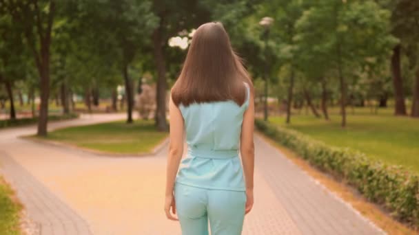 Вид сзади крупным планом женщина, идущая по улице повернуть лицом к камере городской парк летние наружные — стоковое видео