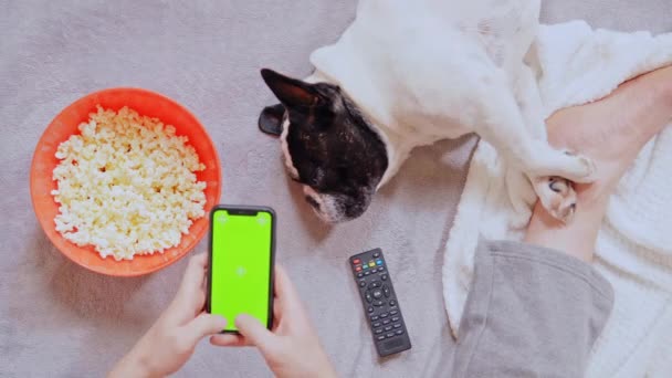 Man eating popcorn holding smartphone indoors — Stock video