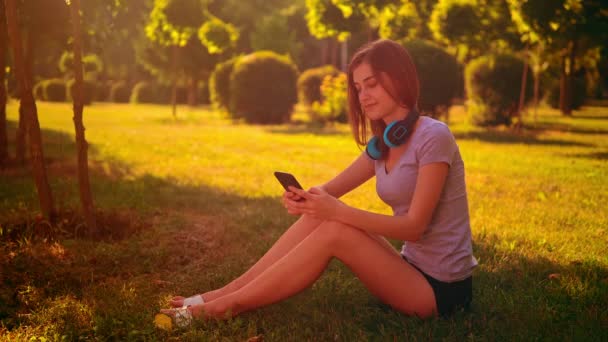 Kavkazský student drží mobilní odpočinek v parku — Stock video