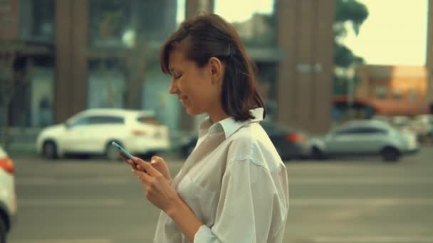 Erwachsene Frau nutzt mobile Spaziergänge in der Stadt — Stockvideo