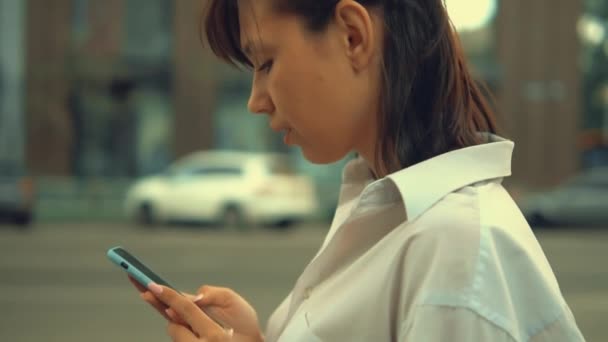 Mujer adulta escribiendo mensaje camina en la ciudad — Vídeo de stock