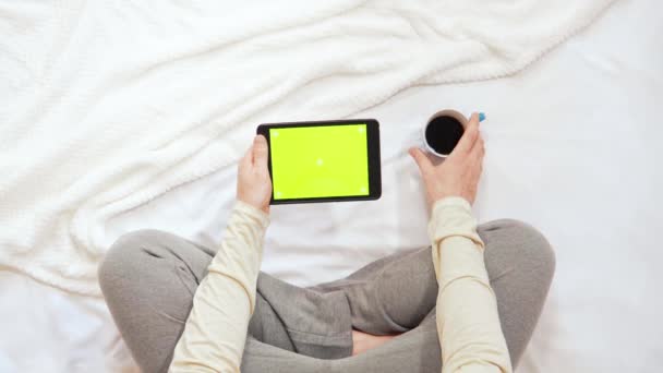 Верхний вид человек сидит на кровати с помощью устройства с зеленым экраном — стоковое видео