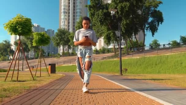 Smiling mixed race millennials stroll outdoors using smartphone cityscape background — Stock Video