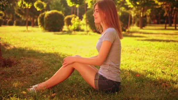 Fröhliches Weibchen sitzt auf dem Rasen — Stockvideo