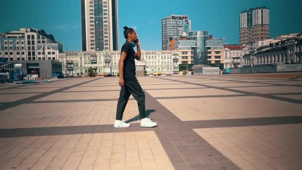 Jóképű srác telefonbeszélgetés sétál a téren — Stock videók
